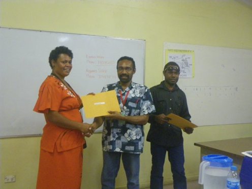 Fijian National Mareta Saun receives her sewing certificate from POM Branch Manager Mr. Bernard Paru. Looking on is the Adult Literacy Program Manager Mr Aquino Saklo. 