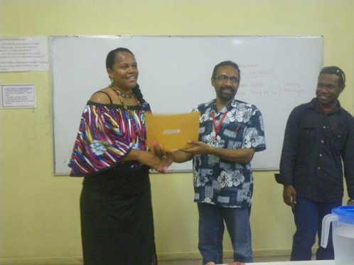 Fijian National Mere Mainakavika  receives her sewing certificate from POM Branch Manager Mr. Bernard Paru. Looking on is the Adult Literacy Program Manager Mr Aquino Saklo. 